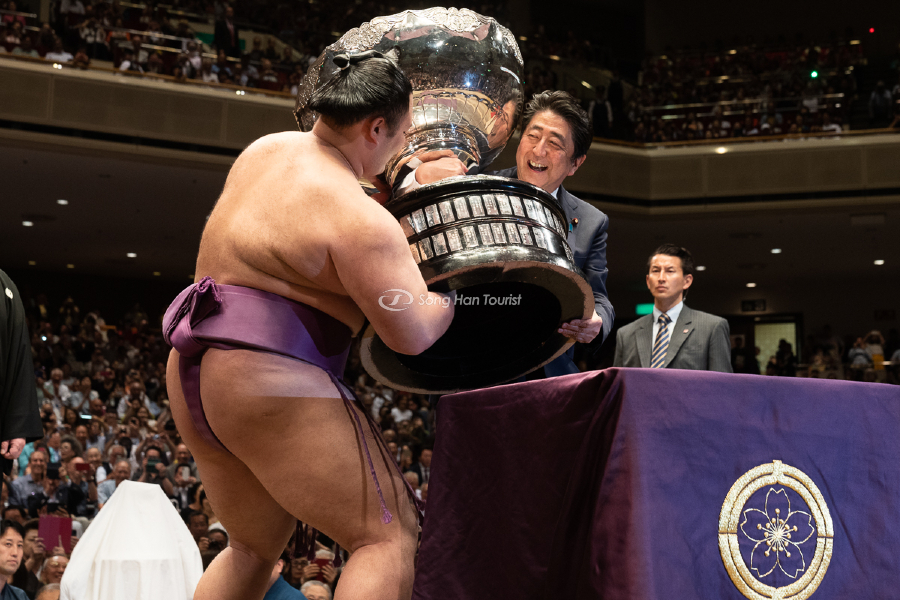 Một sumo đang nhận chiếc cúp vô địch do Thủ tướng Nhật Shinzo Abe trao tặng